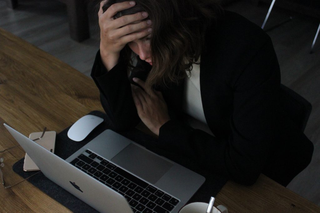 Femme avec la main sur la tête devant un ordinateur, l'air stressé.
