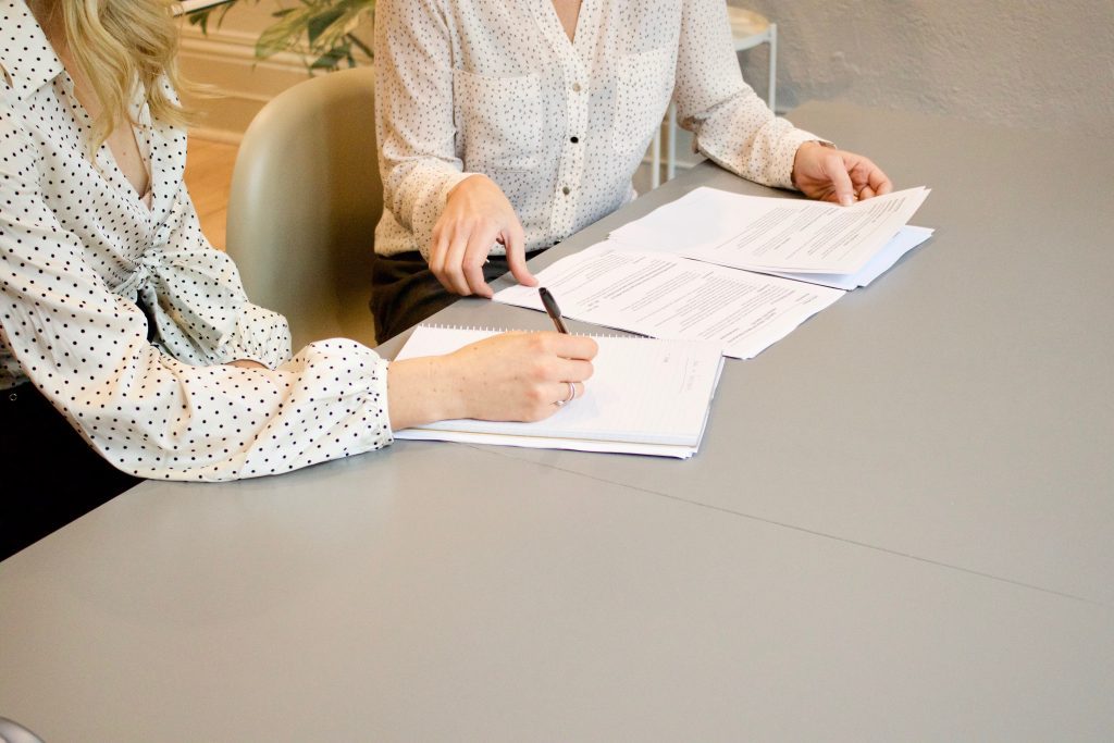 Two women's arms with resumés on table