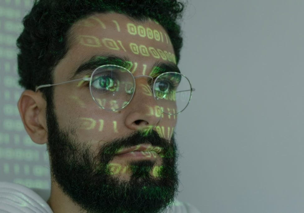 Close up of male with tech coding language projected on his face