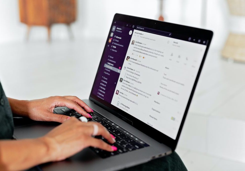 Woman's hands on laptop looking at Slack channel