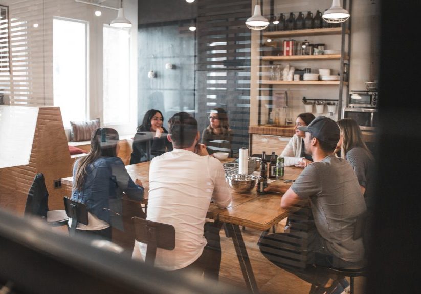 des personnes assises autour d'une table dans une salle de réunion montrant la diversité sur le lieu de travail